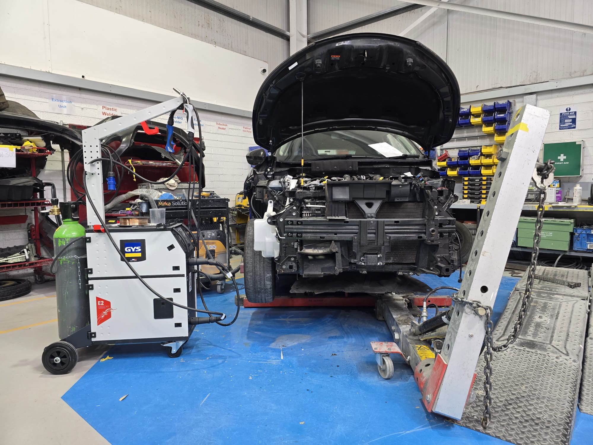 Vehicle raised in workshop showing dark scrim above it for inspecting paint job