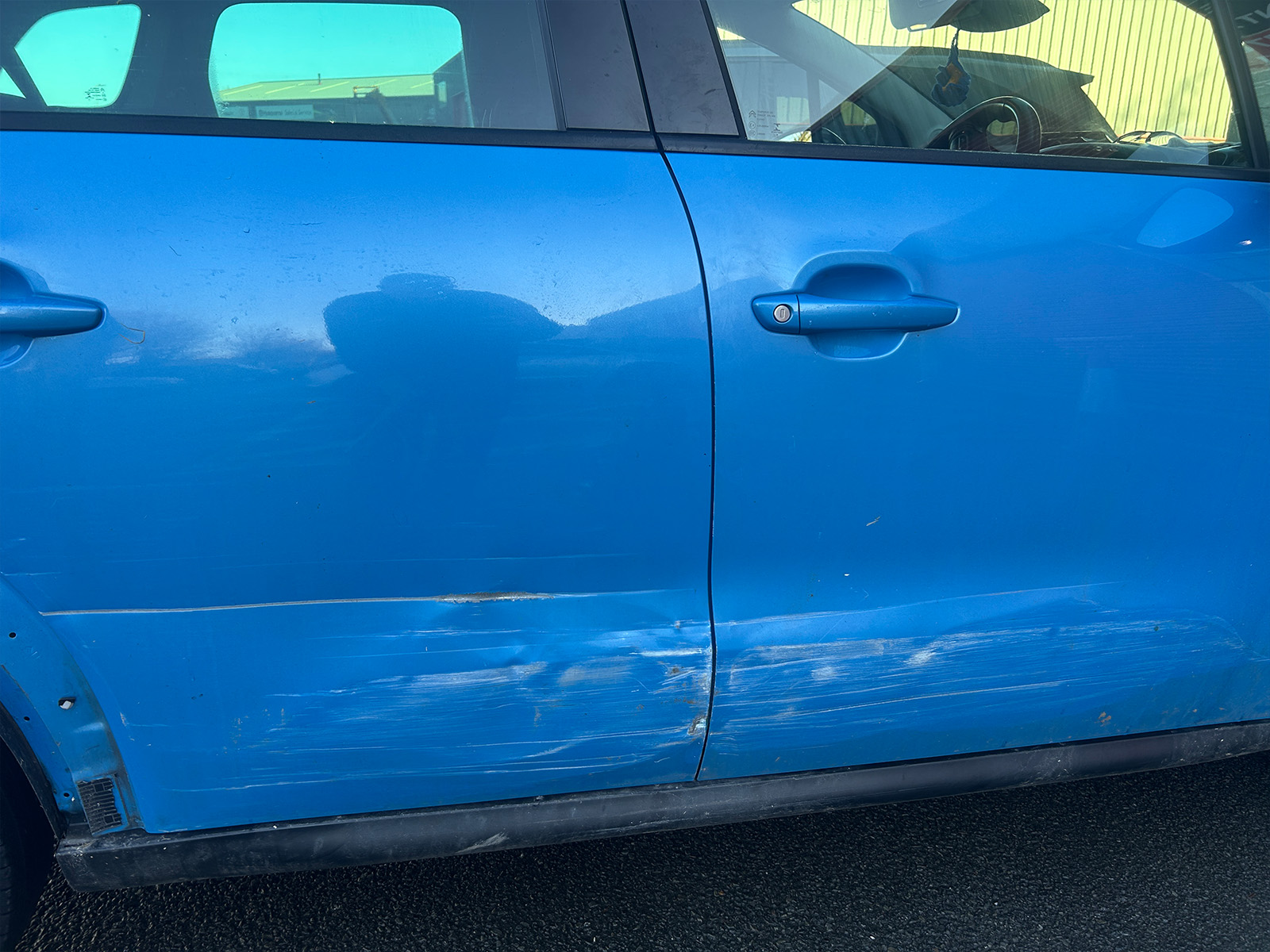Blue Citroen C3 side view close-up of scratched door panels.