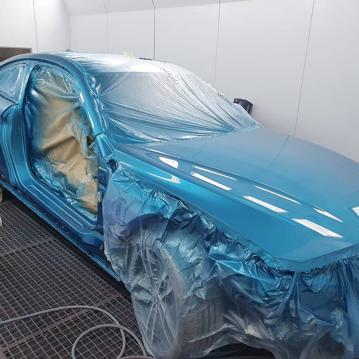 Blue BMW in spray booth showing work in progress